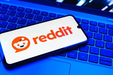 Prag, Çek Cumhuriyeti - 08 01 2025: Dizüstü bilgisayarın üzerinde duran bir cep telefonu Reddit logosunu gösterir. Reddit tartışma, haber ve toplum içeriği için bir platformdur.