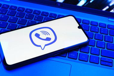 Prag, Çek Cumhuriyeti - 08 01 2025: Dizüstü bilgisayarın üzerinde duran bir cep telefonu Viber logosunu gösteriyor. Viber aramalar, mesajlar ve medya paylaşımı için bir mesajlaşma uygulamasıdır.