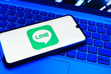 Prag, Çek Cumhuriyeti - 08 01 2025: Dizüstü bilgisayarın üzerinde duran bir cep telefonu Hat logosunu gösterir. Line aramalar, mesajlar ve çokluortam paylaşımı için bir mesajlaşma uygulamasıdır.