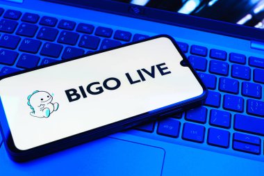 Prag, Çek Cumhuriyeti - 08 01 2025: Dizüstü bilgisayarın üzerinde duran bir cep telefonu Bigo Live logosunu gösteriyor. Bigo Live canlı yayın ve sosyal etkileşim için bir platformdur.