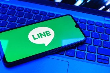 Prag, Çek Cumhuriyeti - 08 01 2025: Dizüstü bilgisayarın üzerinde duran bir cep telefonu Hat logosunu gösterir. Line aramalar, mesajlar ve çokluortam paylaşımı için bir mesajlaşma uygulamasıdır.