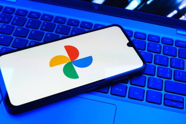 Prag, Çek Cumhuriyeti - 08 01 2025: Laptop klavyesinde duran bir cep telefonu Google Photos logosunu görüntüler. Google Fotoğrafları fotoğraf ve videoları saklamak ve düzenlemek için bir platformdur.