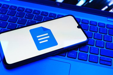 Prag, Çek Cumhuriyeti - 08 01 2025: Dizüstü bilgisayarda bulunan bir cep telefonu Google Docs logosunu görüntüler. Google Docs metin belgeleri oluşturmak ve düzenlemek için bir platformdur.