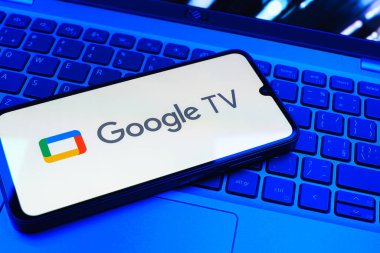 Prag, Çek Cumhuriyeti - 08 01 2025: Laptop klavyesinde uzanan bir cep telefonu Google TV logosunu gösteriyor. Google TV film, program ve uygulamalar için bir platformdur..