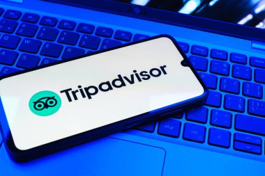 Prag, Çek Cumhuriyeti - 08 01 2025: Dizüstü bilgisayarın üzerinde bulunan bir cep telefonu TripDanışman logosunu gösteriyor. Seyahat danışmanı seyahat değerlendirmeleri, rezervasyonlar ve tavsiyeler için bir platformdur..
