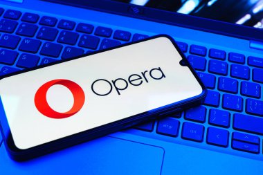 Prag, Çek Cumhuriyeti - 08 01 2025: Dizüstü bilgisayarın üzerinde duran bir cep telefonu Opera logosunu gösteriyor. Opera hızlı ve güvenli internet taraması için bir web tarayıcısıdır.