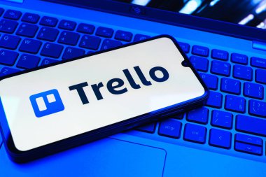 Prag, Çek Cumhuriyeti - 08 01 2025: Dizüstü bilgisayarın üzerinde duran bir cep telefonu Trello logosunu gösterir. Trello, tahta ve görevleri kullanarak proje yönetimi için bir platformdur.