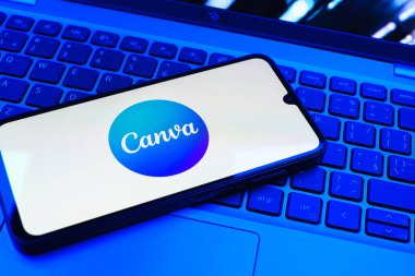 Prag, Çek Cumhuriyeti - 08 01 2025: Laptop klavyesinde duran bir cep telefonu Canva logosunu gösteriyor. Canva grafik, sunum ve tasarımlar yaratmak için bir platformdur..
