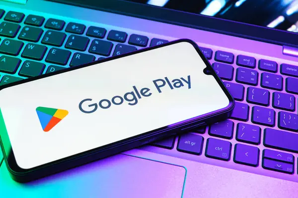 Prag, Çek Cumhuriyeti - 08 01 2025: Dizüstü bilgisayarda bulunan bir cep telefonu Google Play logosunu görüntüler. Google Play uygulamaları, oyunları ve dijital içeriği indirmek için bir platformdur.