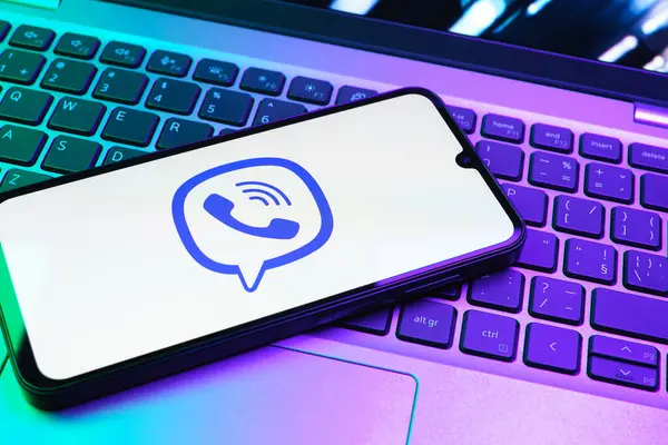 Prag, Çek Cumhuriyeti - 08 01 2025: Dizüstü bilgisayarın üzerinde duran bir cep telefonu Viber logosunu gösteriyor. Viber aramalar, mesajlar ve medya paylaşımı için bir mesajlaşma uygulamasıdır.