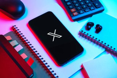 Prag, Çek Cumhuriyeti - 08 18 2025: Merkezinde X logosu sergilenen bir cep telefonu ile ofis malzemeleri düzenlemesi. X, kısa gönderileri ve güncellemeleri paylaşmak için bir platformdur.