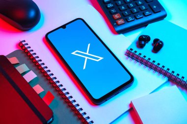 Prag, Çek Cumhuriyeti - 08 18 2025: Merkezinde X logosu sergilenen bir cep telefonu ile ofis malzemeleri düzenlemesi. X, kısa gönderileri ve güncellemeleri paylaşmak için bir platformdur.