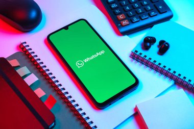 Prag, Çek Cumhuriyeti - 08 18 2025: Ofis malzemelerinin merkezde WhatsApp logosunu gösteren bir cep telefonu ile düzenlenmesi. WhatsApp mesaj, çağrı ve medya göndermek için bir uygulamadır.
