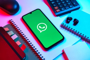 Prag, Çek Cumhuriyeti - 08 18 2025: Ofis malzemelerinin merkezde WhatsApp logosunu gösteren bir cep telefonu ile düzenlenmesi. WhatsApp mesaj, çağrı ve medya göndermek için bir uygulamadır.