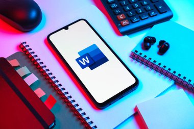 Prag, Çek Cumhuriyeti - 08 18 2025: Merkezinde Word logosu sergilenen bir cep telefonu ile ofis malzemeleri düzenlemesi. Word belge yaratmak ve düzenlemek için bir yazılımdır..