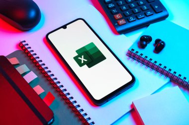 Prag, Çek Cumhuriyeti - 08 18 2025: Excel logosu sergilenen bir cep telefonu ile ofis malzemeleri düzenlemesi. Excel, tablo, veri analizi ve hesaplamalar için bir yazılımdır..