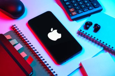 Prag, Çek Cumhuriyeti - 08 18 2025: Merkezi Apple logosunu gösteren bir cep telefonu ile ofis malzemeleri düzenlemesi. Apple iPhone, bilgisayar ve hizmet üreten bir teknoloji şirketidir..