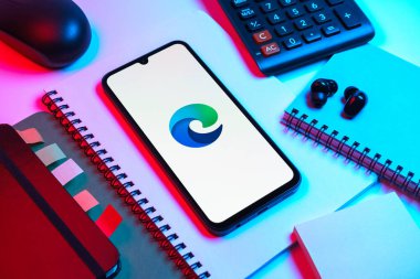 Prag, Çek Cumhuriyeti - 08 18 2025: Merkezde Edge logosunu gösteren bir cep telefonu ile ofis malzemeleri düzenlemesi. Edge, Microsoft tarafından Windows aygıtları için geliştirilen bir web tarayıcısıdır..