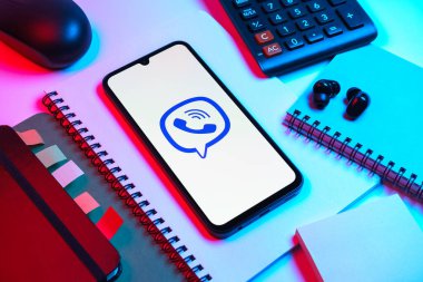 Prag, Çek Cumhuriyeti - 08 18 2025: Merkezde Viber logosunu gösteren bir cep telefonu ile ofis malzemeleri düzenlemesi. Viber aramalar, mesajlar ve medya paylaşımı için bir mesajlaşma uygulamasıdır.