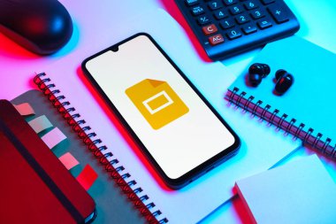 Prag, Çek Cumhuriyeti - 08 18 2025: Merkezde Google Slides logosunu gösteren bir cep telefonu ile ofis malzemeleri düzenlemesi. Google Slides sunumlar ve slayt gösterileri oluşturmak için bir platformdur.