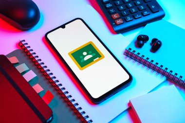 Prag, Çek Cumhuriyeti - 08 18 2025: Merkezde Google Sınıfı logosunu gösteren bir cep telefonu ile ofis malzemeleri düzenlemesi. Google Sınıfı, sınıfları ve eğitim içeriğini yönetmek için bir platformdur.