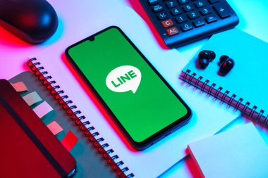 Prag, Çek Cumhuriyeti - 08 18 2025: Merkezinde hat logosu sergilenen bir cep telefonu ile ofis malzemeleri düzenlemesi. Line aramalar, mesajlar ve çokluortam paylaşımı için bir mesajlaşma uygulamasıdır.