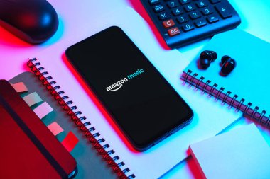 Prag, Çek Cumhuriyeti - 08 18 2025: Merkezde Amazon Müzik logosu sergilenen bir cep telefonu ile ofis malzemeleri düzenlemesi. Amazon Müzik müzik müzik için bir platformdur..