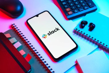 Prag, Çek Cumhuriyeti - 08 18 2025: Merkezde Slack logosu sergilenen bir cep telefonu ile ofis malzemeleri düzenlemesi. Slack takım mesajlaşması ve iş yeri iletişimi için bir platformdur.