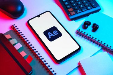 Prag, Çek Cumhuriyeti - 08 18 2025: Ofis malzemelerinin merkezde After Effects logosu sergilenen bir cep telefonu ile düzenlenmesi. After Effects hareket grafikleri ve görsel efektler için bir yazılımdır..