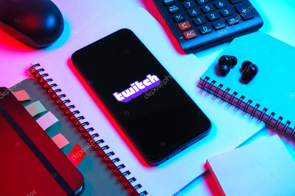 Prague, Czechia - 08 18 2025: An arrangement of office supplies with a mobile phone in the center displaying Twitch logo. Twitch is a platform for live streaming games and content.