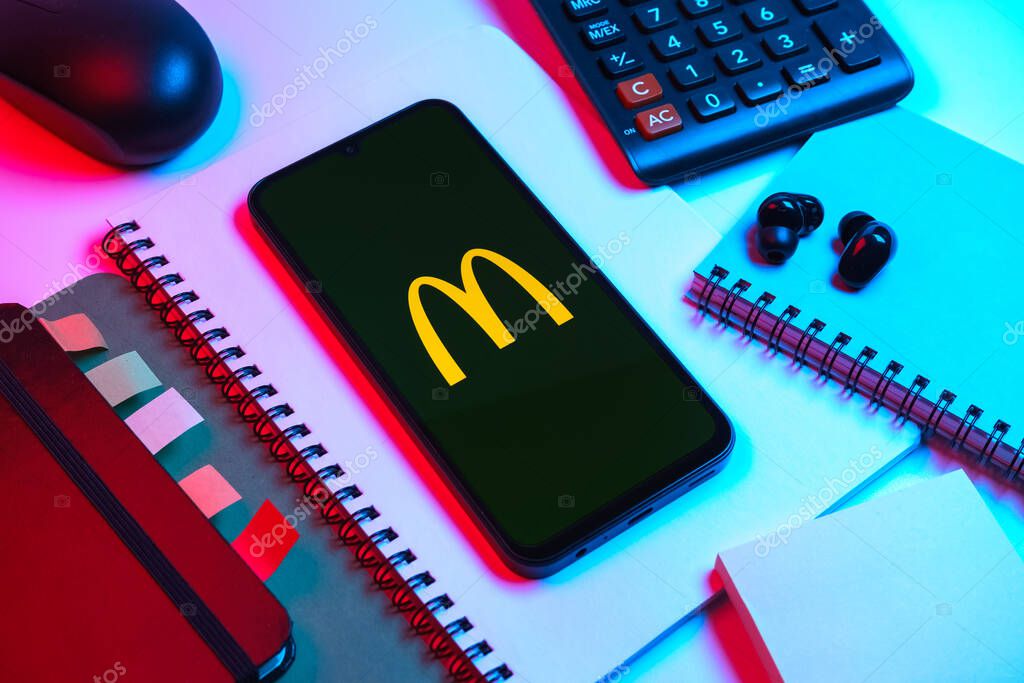 Prague, Czechia - 08 18 2025: An arrangement of office supplies with a mobile phone in the center displaying McDonalds logo. McDonalds is a fast-food chain serving burgers, fries, and more.