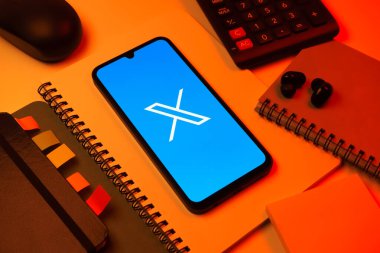Prag, Çek Cumhuriyeti - 08 18 2025: Merkezinde X logosu sergilenen bir cep telefonu ile ofis malzemeleri düzenlemesi. X, kısa gönderileri ve güncellemeleri paylaşmak için bir platformdur.