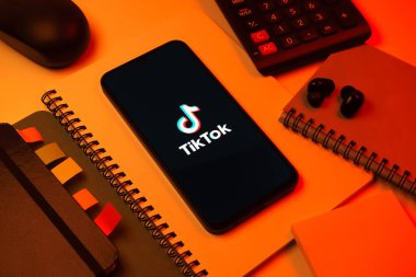 Prag, Çek Cumhuriyeti - 08 18 2025: Merkezde TikTok logosunu gösteren bir cep telefonu ile ofis malzemeleri düzenlemesi. TikTok kısa, yaratıcı ve viral video platformu.