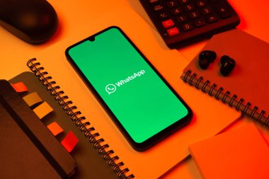 Prag, Çek Cumhuriyeti - 08 18 2025: Ofis malzemelerinin merkezde WhatsApp logosunu gösteren bir cep telefonu ile düzenlenmesi. WhatsApp mesaj, çağrı ve medya göndermek için bir uygulamadır.