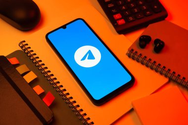 Prag, Çek Cumhuriyeti - 08 18 2025: Merkezde Telegram logosunu gösteren bir cep telefonu ile ofis malzemeleri düzenlemesi. Telgraf hızlı ve güvenli iletiler için bir uygulamadır.