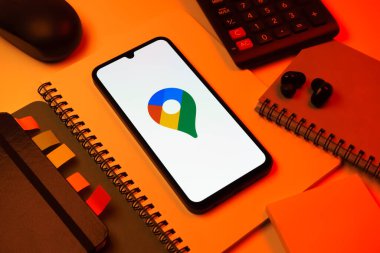 Prag, Çek Cumhuriyeti - 08 18 2025: Merkezde Google Maps logosunu gösteren bir cep telefonu ile ofis malzemeleri düzenlemesi. Google Maps haritalar, navigasyon ve konum hizmetleri için bir platformdur.