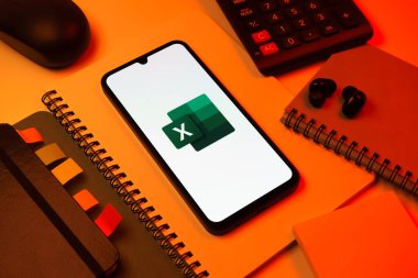 Prag, Çek Cumhuriyeti - 08 18 2025: Excel logosu sergilenen bir cep telefonu ile ofis malzemeleri düzenlemesi. Excel, tablo, veri analizi ve hesaplamalar için bir yazılımdır..