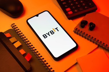 Prag, Çek Cumhuriyeti - 08 18 2025: Merkezde Bybit logosunu gösteren bir cep telefonu ile ofis malzemeleri düzenlemesi. Bybit şifreli para ve türev ticareti için bir platformdur.