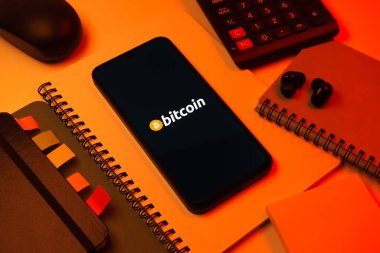 Prag, Çek Cumhuriyeti - 08 18 2025: Merkezde Bitcoin logosu sergilenen bir cep telefonu ile ofis malzemeleri düzenlemesi. Bitcoin merkezi olmayan işlemler için dijital bir kripto para birimidir.