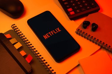 Prag, Çek Cumhuriyeti - 08 18 2025: Merkezde Netflix logosunu gösteren bir cep telefonu ile ofis malzemeleri düzenlemesi. Netflix sinema ve televizyon programları için bir yayın platformudur..