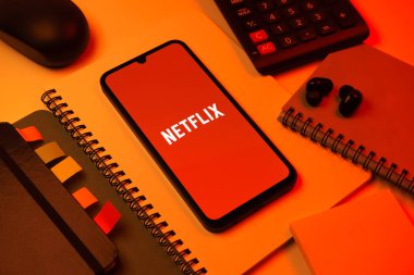 Prag, Çek Cumhuriyeti - 08 18 2025: Merkezde Netflix logosunu gösteren bir cep telefonu ile ofis malzemeleri düzenlemesi. Netflix sinema ve televizyon programları için bir yayın platformudur..