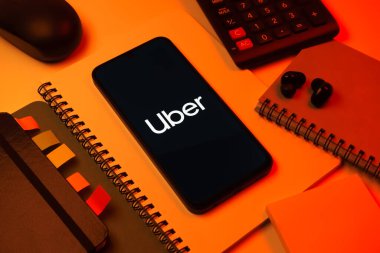 Prag, Çek Cumhuriyeti - 08 18 2025: Merkezde Uber logosu gösteren bir cep telefonu ile ofis malzemeleri düzenlemesi. Uber ulaşım ve dağıtım hizmetleri için bir gezinti selamlama uygulaması.