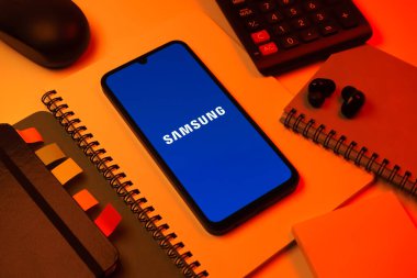 Prag, Çek Cumhuriyeti - 08 18 2025: Merkezde Samsung logosu sergilenen bir cep telefonu ile ofis malzemeleri düzenlemesi. Samsung elektronik ve cihaz üreten bir teknoloji şirketi..