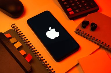 Prag, Çek Cumhuriyeti - 08 18 2025: Merkezi Apple logosunu gösteren bir cep telefonu ile ofis malzemeleri düzenlemesi. Apple iPhone, bilgisayar ve hizmet üreten bir teknoloji şirketidir..