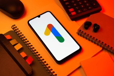 Prag, Çek Cumhuriyeti - 08 18 2025: Merkezinde Google One logosu bulunan bir cep telefonu ile ofis malzemeleri düzenlemesi. Google 1 bulut depolama ve abonelik hizmetleri için bir platformdur.