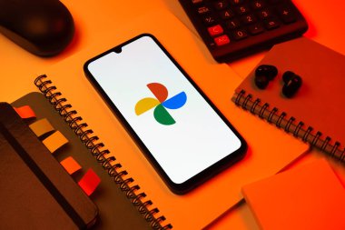 Prag, Çek Cumhuriyeti - 08 18 2025: Merkezde Google Photos logosunu gösteren bir cep telefonu ile ofis malzemeleri düzenlemesi. Google Fotoğrafları fotoğraf ve videoları saklamak ve düzenlemek için bir platformdur.