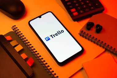 Prag, Çek Cumhuriyeti - 08 18 2025: Merkezde Trello logosu sergilenen bir cep telefonu ile ofis malzemeleri düzenlemesi. Trello, tahta ve görevleri kullanarak proje yönetimi için bir platformdur.