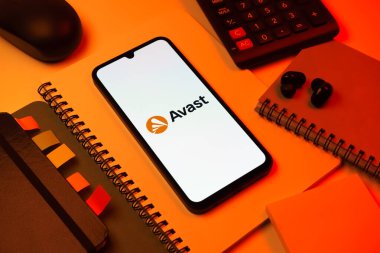 Prag, Çek Cumhuriyeti - 08 18 2025: Avast logosunu gösteren bir cep telefonu ile ofis malzemeleri düzenlemesi. Avast antivirüs ve siber güvenlik için bir platformdur.