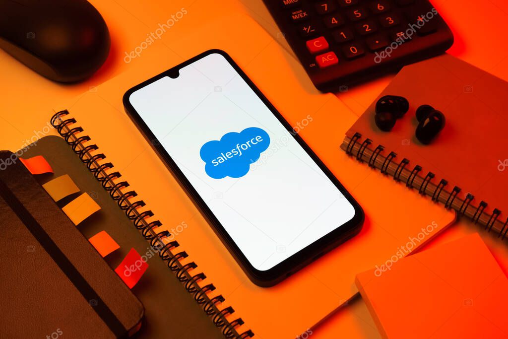 Prague, Czechia - 08 18 2025: An arrangement of office supplies with a mobile phone in the center displaying Salesforce logo. Salesforce is a platform for customer relationship management and cloud services.