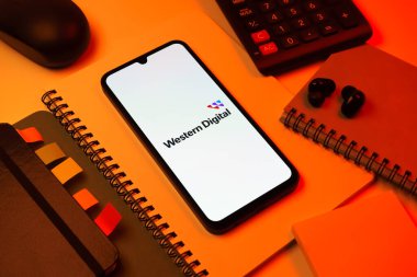 Prag, Çek Cumhuriyeti - 08 18 2025: Merkezde Batı Dijital logosunu gösteren bir cep telefonu ile ofis malzemeleri düzenlemesi. Western Digital, veri depolama cihazları ve çözümleri üreten bir şirkettir..